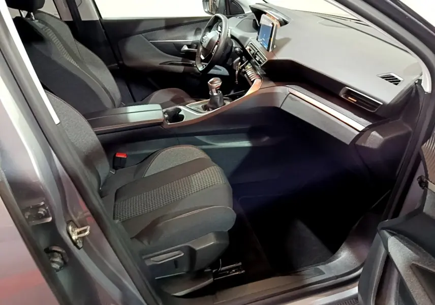 Vue intérieure côté conducteur du Peugeot 3008 gris clair, mettant en valeur le tableau de bord moderne avec écran tactile et volant cuir.