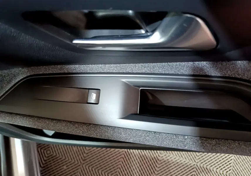 Gros plan sur la poignée intérieure et commande de lève-vitre côté conducteur d’un Peugeot 3008 gris clair 2020.