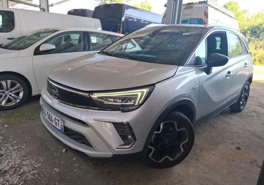 Vue 3/4 avant d’un Opel Crossland gris clair 2024 avec phares LED et jantes noires au design distinctif.