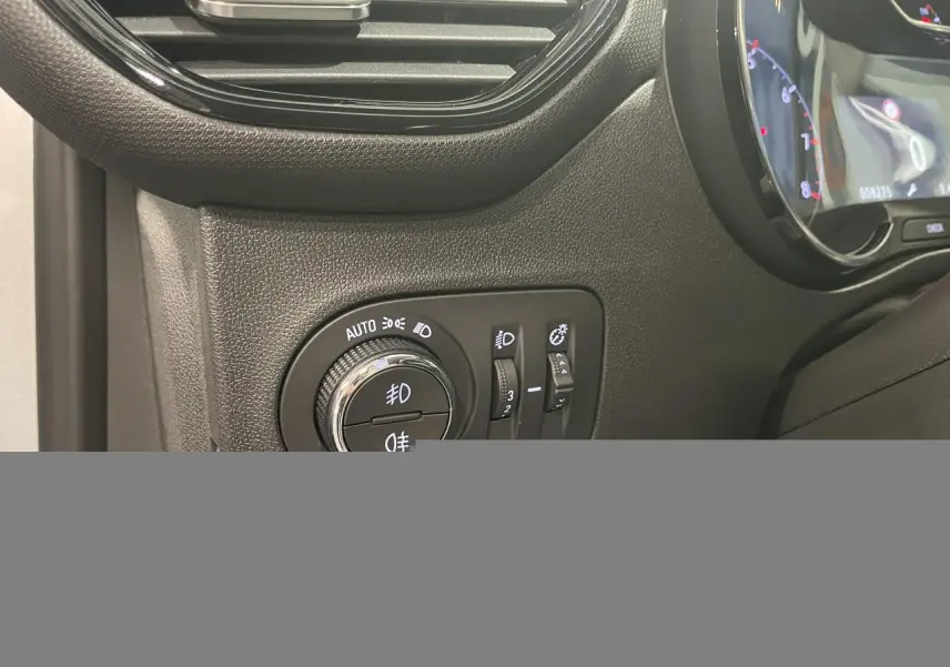 Détail du tableau de bord côté gauche de l’Opel Crossland gris clair 2024, avec commandes d’éclairage et compteur numérique partiel.