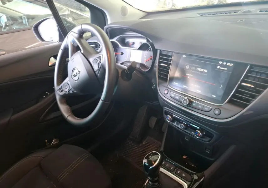 Vue intérieure côté conducteur de l’Opel Crossland gris clair 2024, avec volant multifonction et écran tactile central allumé.