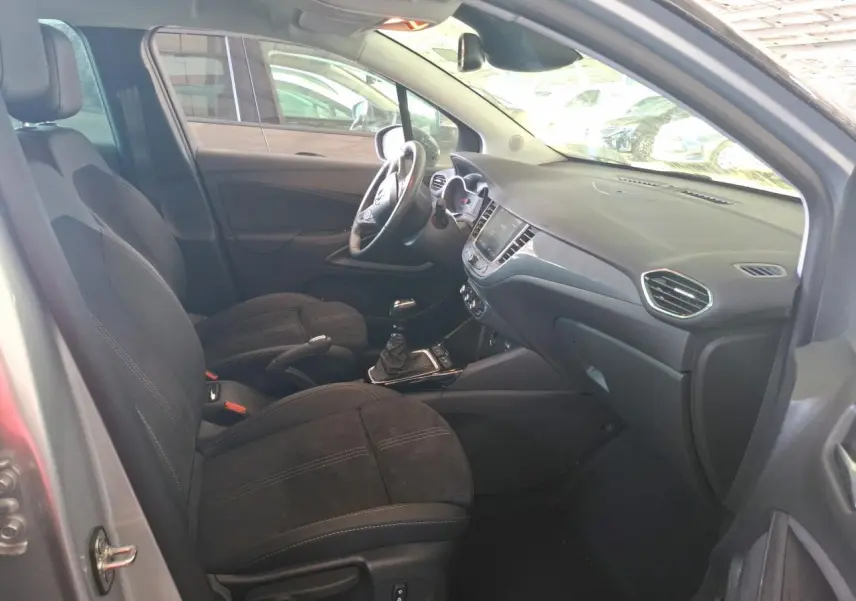 Vue intérieure côté conducteur de l'Opel Crossland gris clair 2024, avec sièges noirs et boîte manuelle visible.