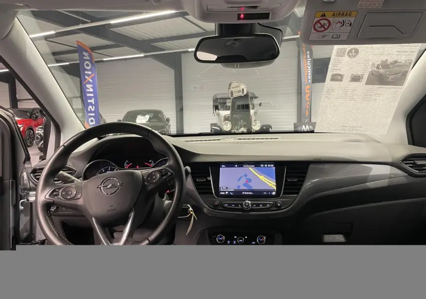 Vue intérieure avant de l’Opel Crossland gris clair 2024, volant cuir, écran tactile 8 pouces avec navigation affichée.
