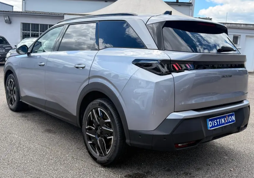 Vue 3/4 arrière droite du Peugeot 5008 Hybrid 145 gris Artense avec vitres teintées et jantes noires distinctives.
