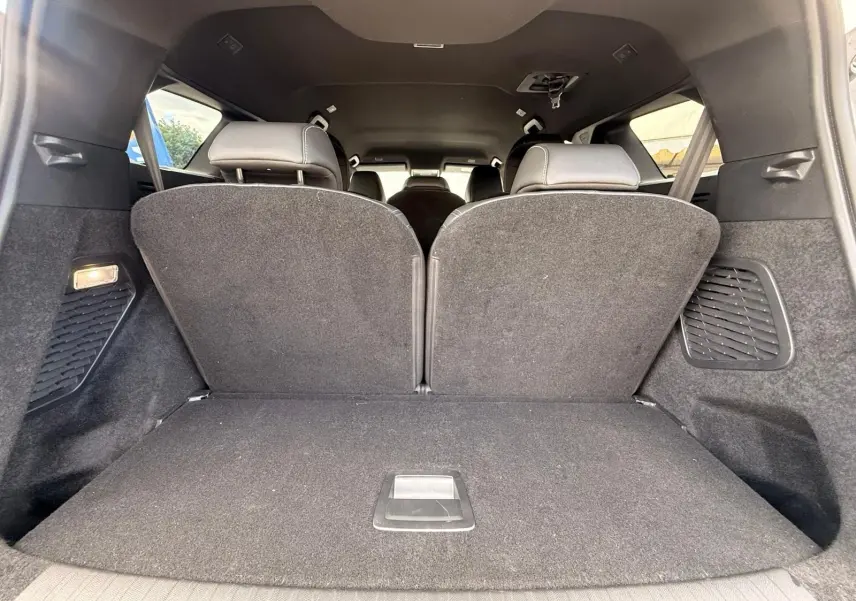 Vue intérieure du coffre du Peugeot 5008 Hybrid 145 gris Artense, montrant les sièges arrière relevés et l'espace de chargement.
