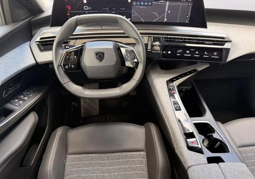 Vue intérieure frontale du tableau de bord gris artense du Peugeot 5008 Hybrid 145 avec écran tactile et volant compact multifonction.
