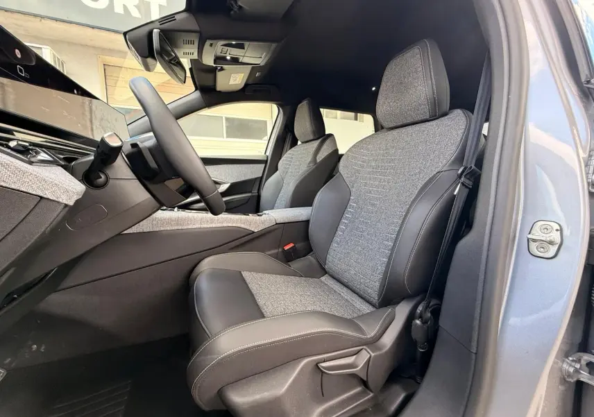 Vue intérieure côté conducteur du Peugeot 5008 Hybrid 145 en gris Artense, sièges tissu et cuir bi-matière visibles.