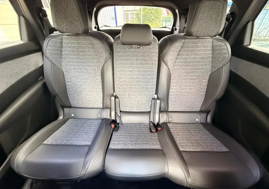 Vue intérieure arrière montrant les trois sièges gris et noirs du Peugeot 5008 Hybrid 2025 avec finition tissu et cuir.