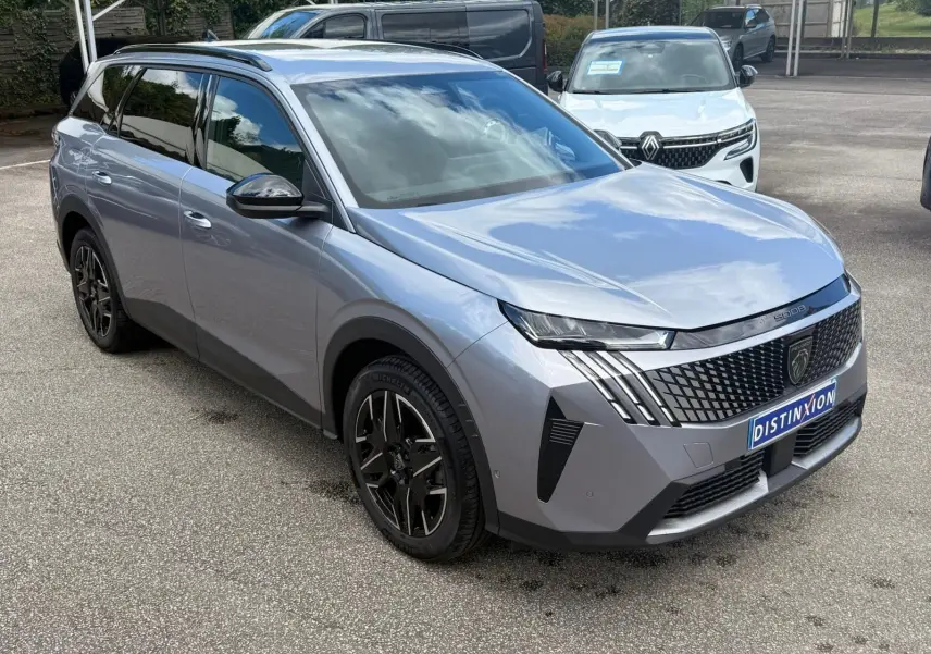Peugeot 5008 Hybrid gris Artense en 3/4 avant droit, avec calandre distinctive et jantes noires stylées.