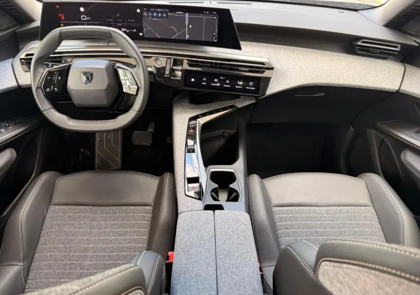 Vue intérieure frontale du poste de conduite du Peugeot 5008 Hybrid 145, avec volant compact et tableau de bord numérique.