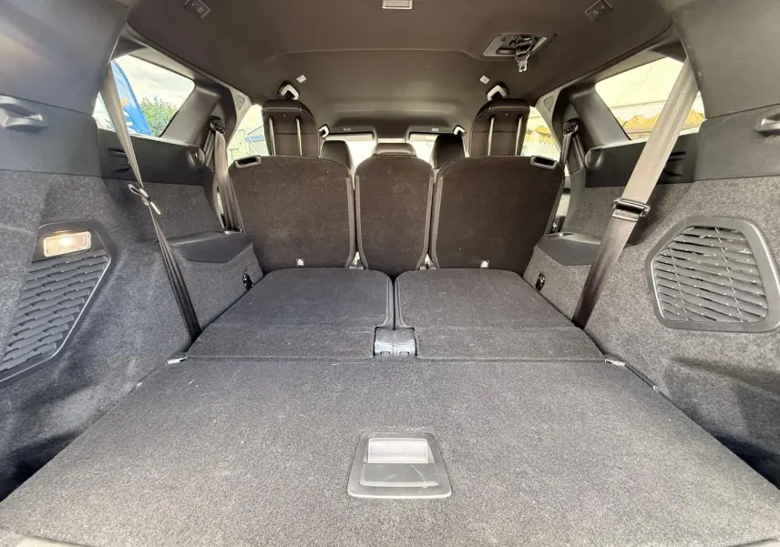 Vue intérieure arrière du coffre du Peugeot 5008 hybride 2025, sièges rabattus et habillage noir.