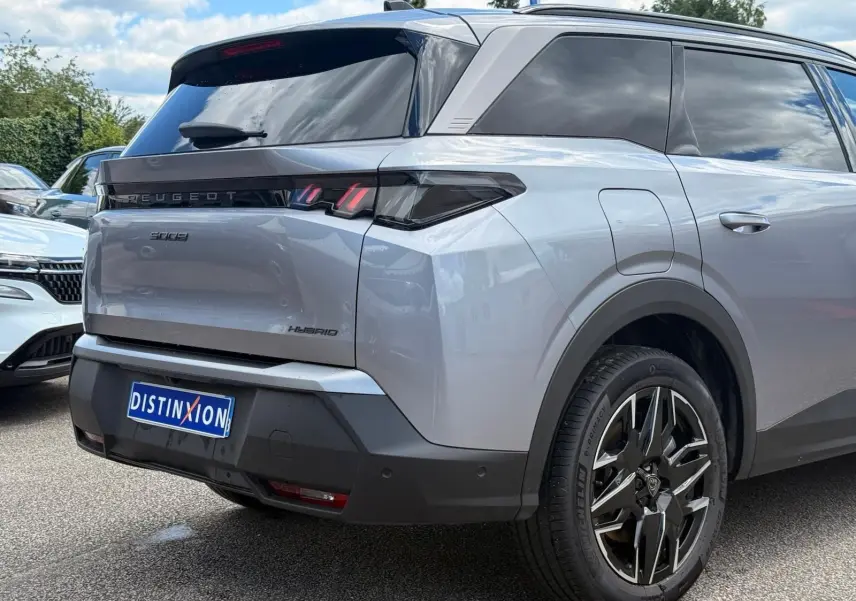 Vue 3/4 arrière droite du Peugeot 5008 Hybrid gris Artense avec feux arrière LED et jantes alliage distinctives.