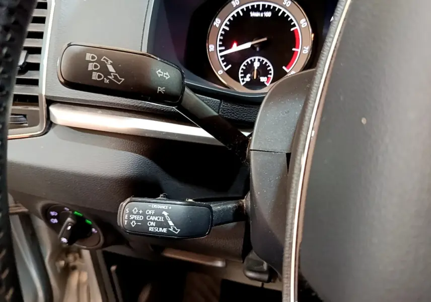 Gros plan sur les commandes au volant et le compteur du Skoda Karoq 1.5 TSI gris clair, tableau de bord intérieur.