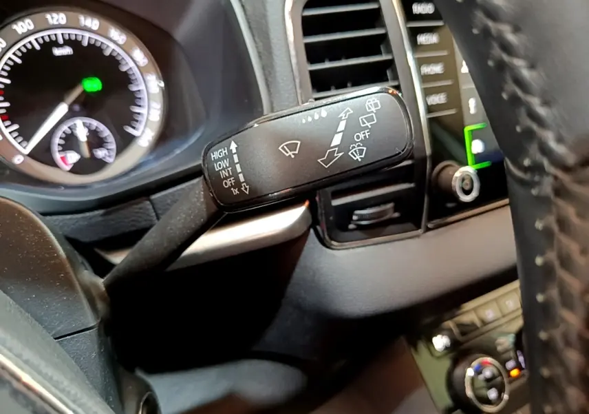 Gros plan sur la commande d’essuie-glace à gauche du volant cuir dans le tableau de bord noir du Skoda Karoq gris clair.