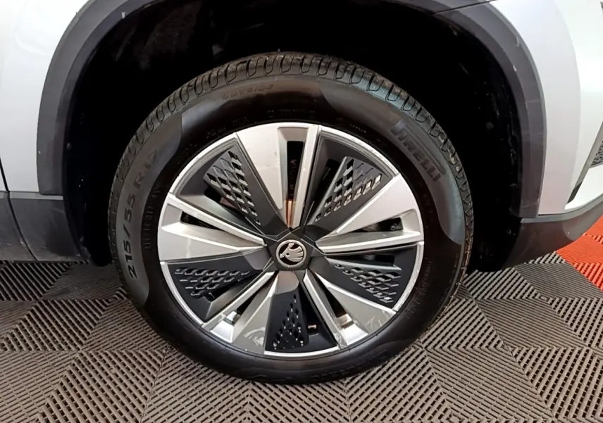 Gros plan sur la roue avant droite d’un Skoda Karoq gris clair avec jante alliage moderne à motifs géométriques.