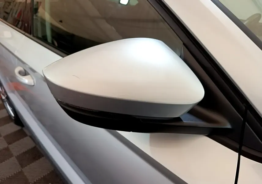 Rétroviseur côté gauche gris clair du Skoda Karoq 2022, avec portière et poignée visibles en arrière-plan.