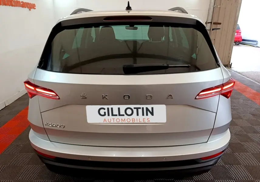 Vue arrière d’un Skoda Karoq gris clair 2022 avec feux LED allumés et logo ŠKODA bien visible.