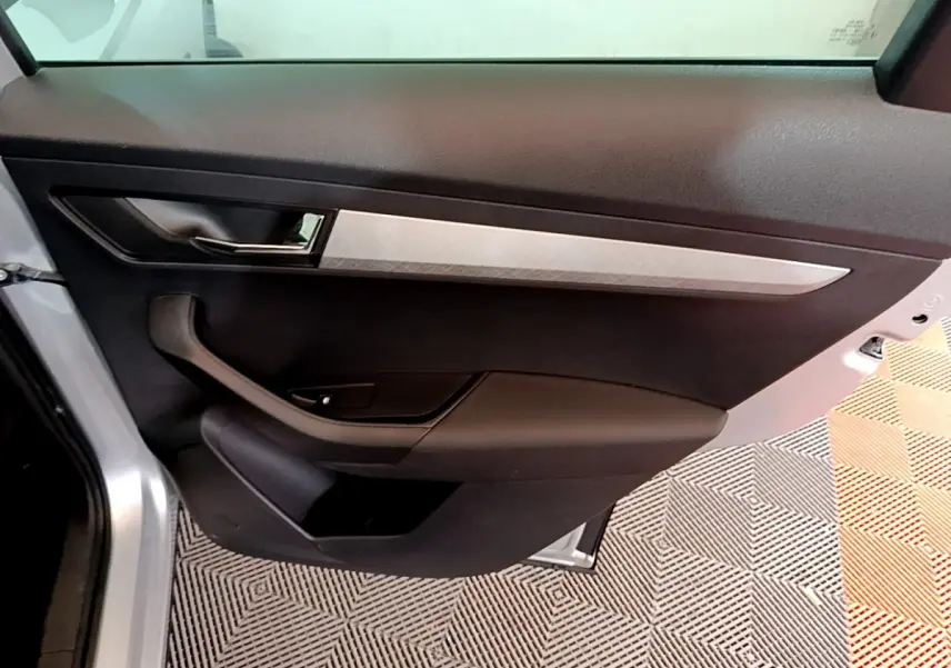 Vue intérieure de la porte arrière gauche gris clair du Skoda Karoq 2022 avec insert décoratif argenté et poignée noire.