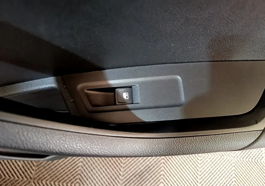 Gros plan sur le bouton d'ouverture du coffre dans l'habitacle noir d'une Skoda Karoq 2022.