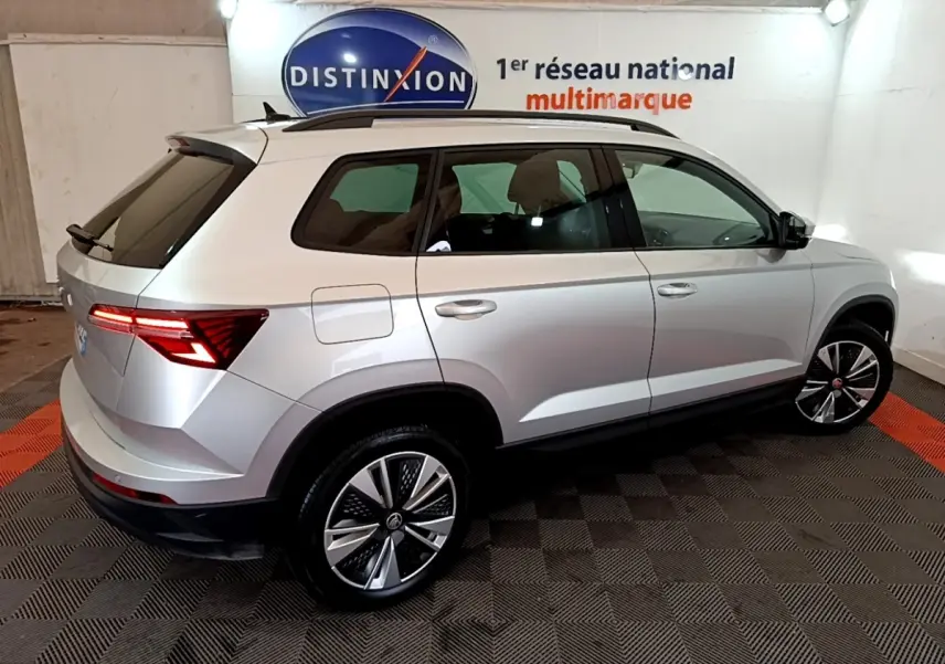 Vue 3/4 arrière droite d’un Skoda Karoq gris clair 2022 avec feux arrière LED et jantes alliage distinctives.