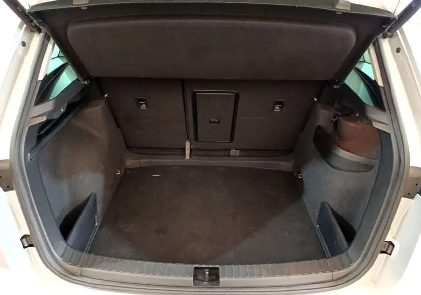 Coffre ouvert vu de l'arrière d'un Skoda Karoq gris clair, montrant un espace de chargement propre et spacieux.
