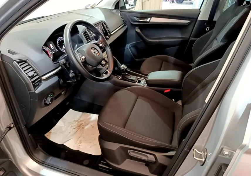 Vue intérieure côté conducteur du Skoda Karoq gris clair 2022, montrant le tableau de bord et les sièges noirs.