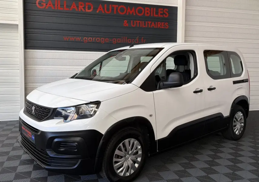 Vue 3/4 avant droit d’un Peugeot Rifter blanc 2021 avec pare-chocs noirs et jantes acier.
