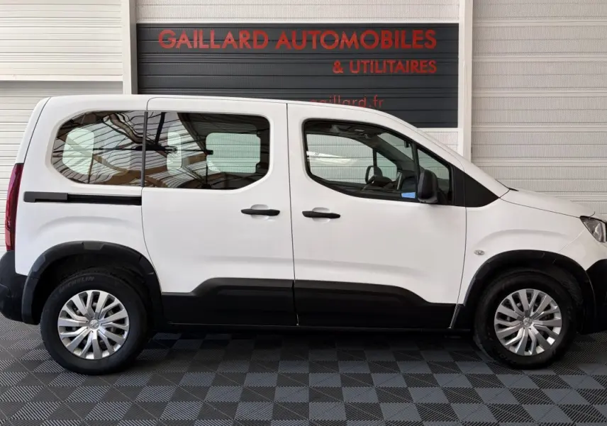 Vue de profil côté gauche d’un Peugeot Rifter blanc 2021 avec protections noires sur les bas de caisse et jantes alliage.