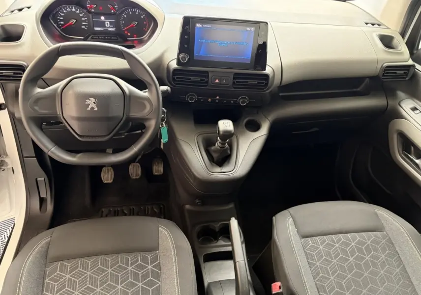Vue intérieure avant du Peugeot Rifter blanc 2021, volant compact, tableau de bord numérique et levier de vitesses manuel.