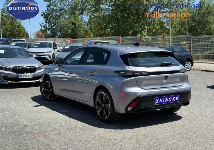 Peugeot e-308 gris métallisé en 3/4 arrière droit, avec feux arrière LED et jantes alliage visibles.