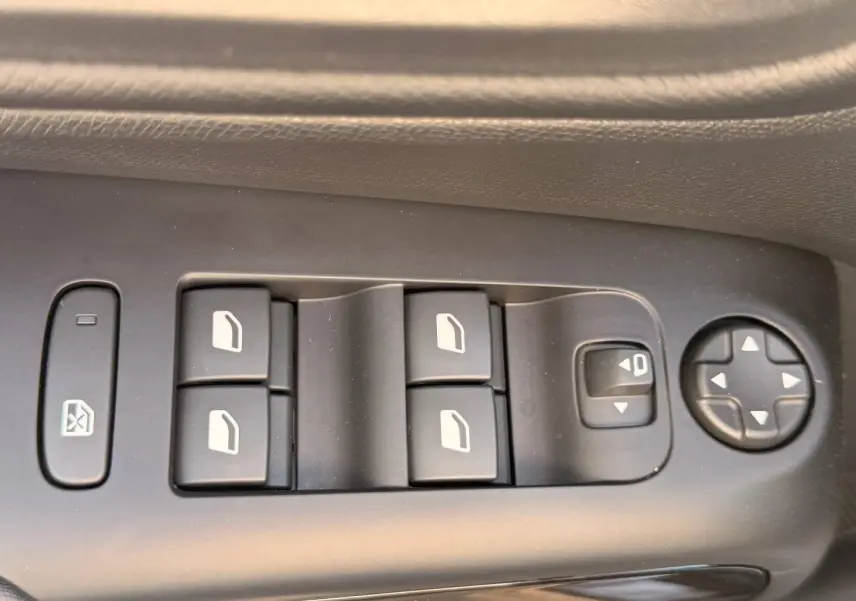 Gros plan sur les commandes de lève-vitres et réglage des rétroviseurs côté conducteur du Citroën C5 Aircross gris Platinium.