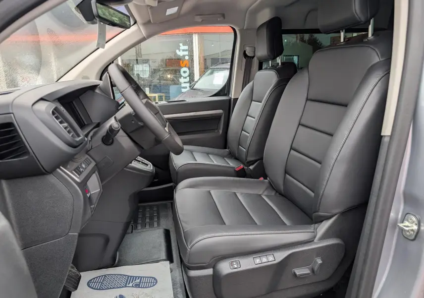 Vue intérieure côté conducteur du Citroën Jumpy gris 2026, sièges avant cuir noir avec réglages électriques.