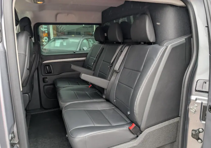 Vue intérieure côté droit sur la banquette cuir noire 3 places du Citroën Jumpy gris avec accoudoir central relevé.