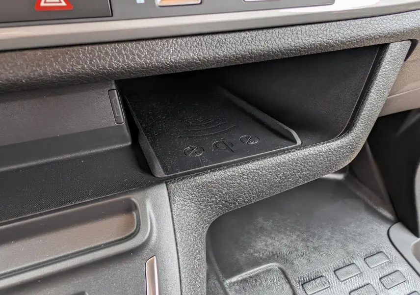Détail du rangement central avec chargeur sans fil dans l’habitacle noir du Citroën Jumpy gris.