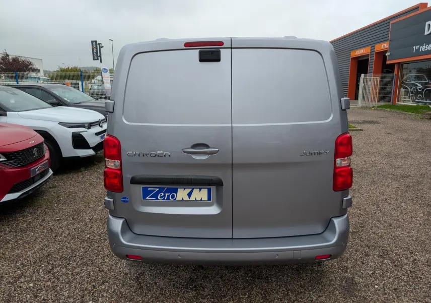 Vue arrière d'un Citroën Jumpy gris avec portes battantes et plaque Zéro KM visible sur un parking.