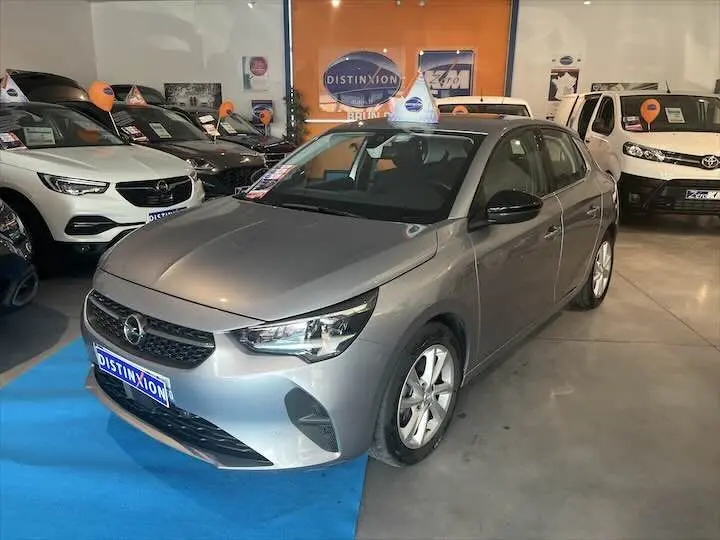 Opel Corsa gris métal vue 3/4 avant droit dans un showroom avec d'autres véhicules en arrière-plan