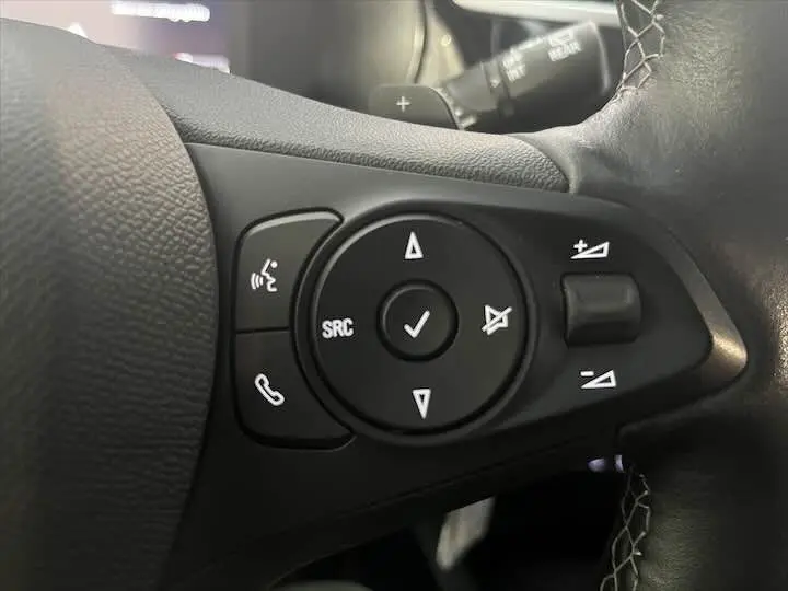 Gros plan sur les commandes multifonctions au volant en cuir noir de l'Opel Corsa gris métal, version Elegance 2021.