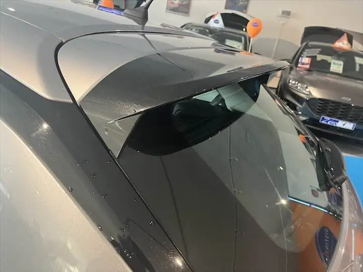 Détail du toit et de la lunette arrière noire d'une Opel Corsa gris métal vue en plongée dans un showroom.