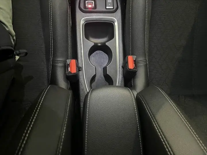 Vue rapprochée de la console centrale noire de l'Opel Corsa 1.2T 100 CH Elegance avec accoudoirs et ceintures rouges.