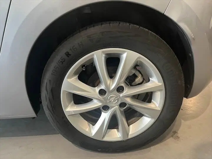 Gros plan sur la roue avant gauche gris métal d'une Opel Corsa 1.2T 100 CH ELEGANCE BVA8 avec jante alliage.