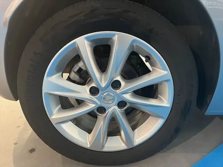 Gros plan sur la jante alliage argentée avec logo Opel d'une Opel Corsa gris métal, roue avant droite visible.