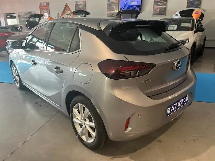 Opel Corsa gris métal vue 3/4 arrière droit en intérieur avec logo Distinxion sur plaque avant