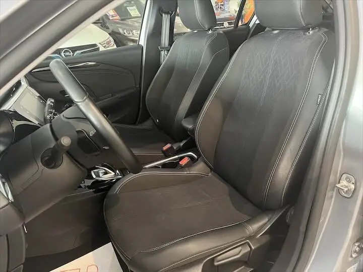 Vue intérieure côté conducteur de l'Opel Corsa gris métal 2021, sièges noirs en tissu et cuir avec surpiqûres blanches.