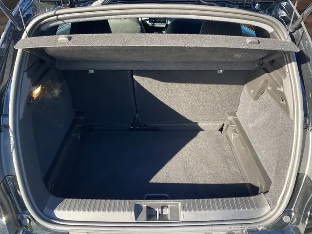 Coffre ouvert vu de l'arrière d'un Renault Captur noir 2024, montrant un espace de chargement propre et bien éclairé.