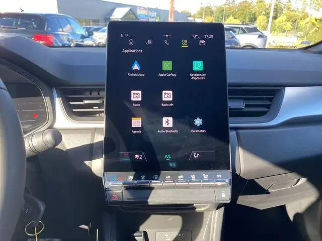 Vue intérieure centrée sur l'écran tactile vertical du tableau de bord du Renault Captur noir 2024, avec volant partiel à gauche.