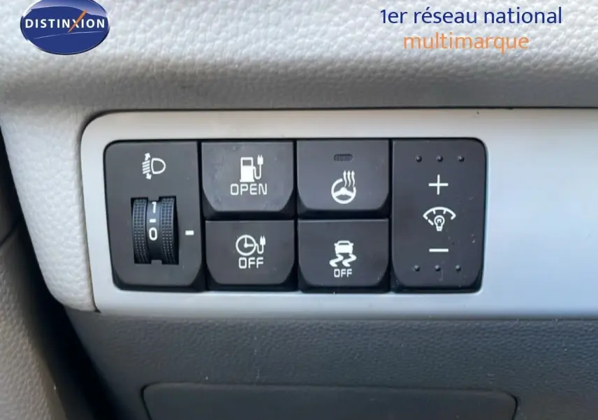 Gros plan sur les commandes électriques et de sécurité du tableau de bord d'une KIA Soul EV 2016, intérieur gris.