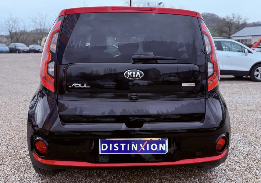 Vue de profil droit d'une KIA SOUL EV électrique noire avec toit et rétroviseur rouge, sur fond neutre.