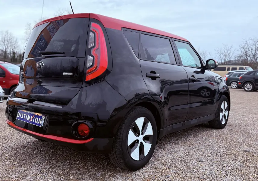 Vue 3/4 arrière droite d'une Kia Soul EV électrique noire avec toit rouge, sur fond neutre avec logo Distinxion.