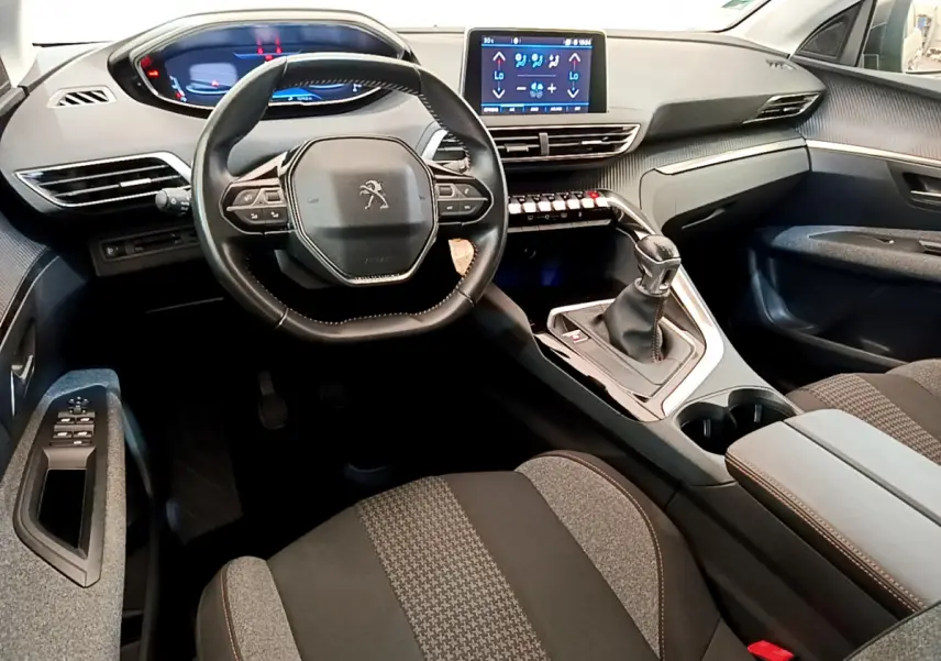 Vue intérieure avant du Peugeot 3008 gris foncé 2020, volant cuir multifonctions et écran tactile central lumineux.