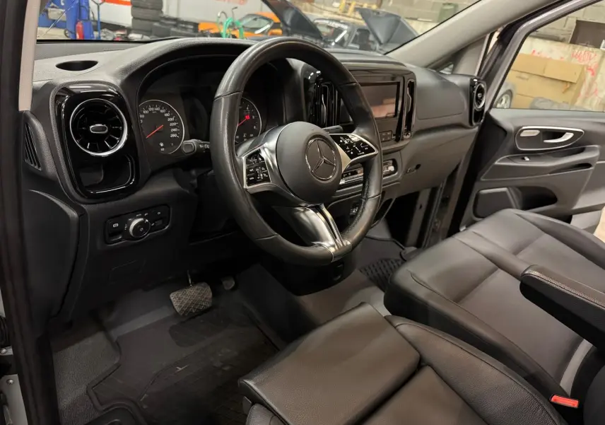 Vue intérieure côté conducteur du Mercedes Vito Mixto 2025, volant cuir, sièges noirs et tableau de bord moderne.